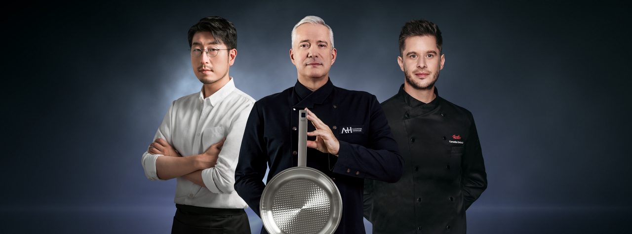 Proud multi ethnic team of chef, sous chefs and cooking assistants looking at camera smiling with arms crossed