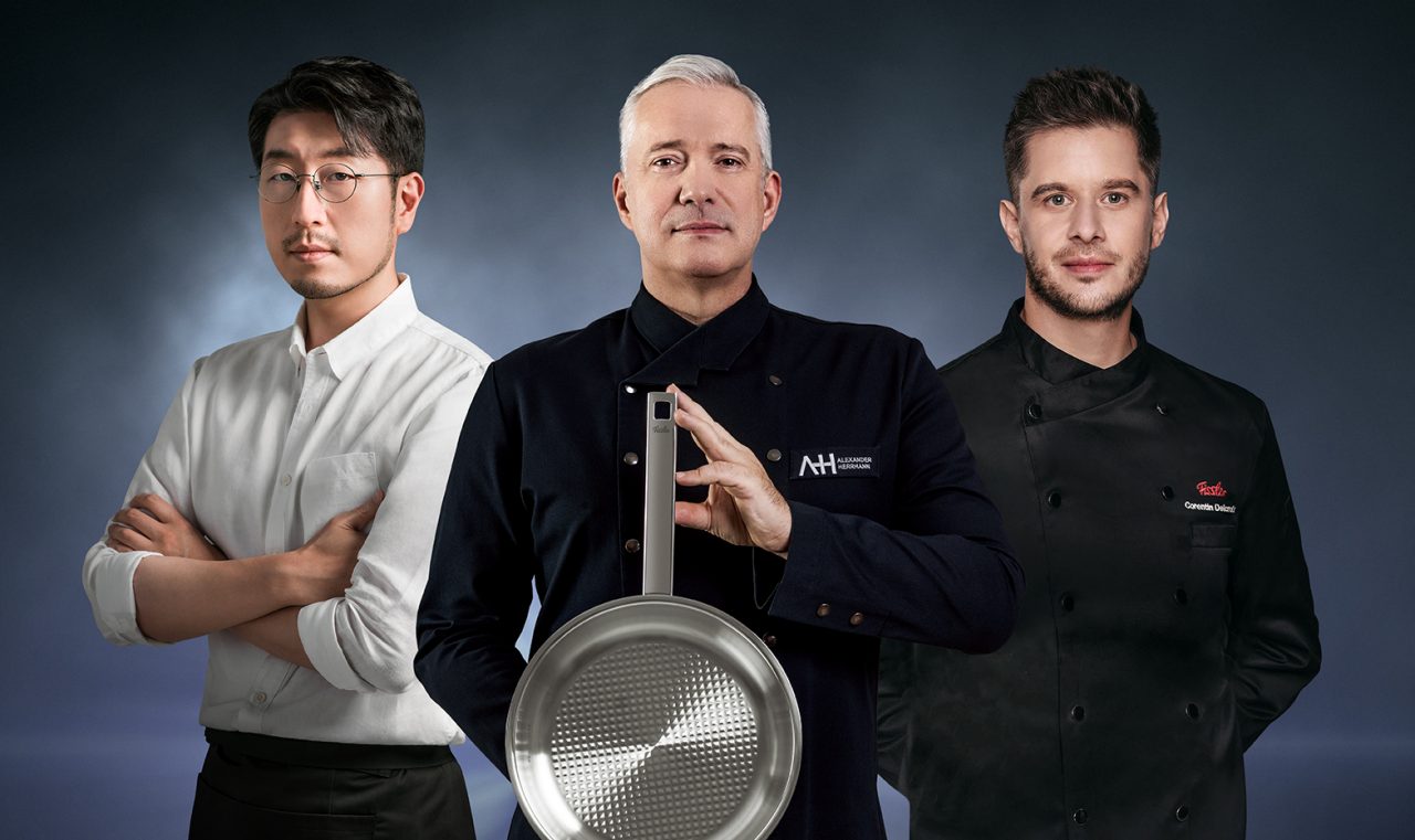 Proud multi ethnic team of chef, sous chefs and cooking assistants looking at camera smiling with arms crossed